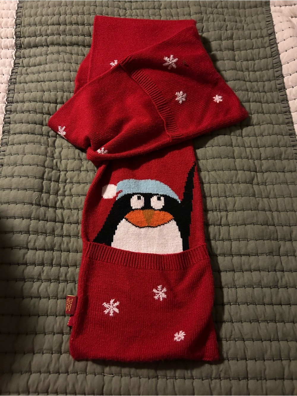 Red knit scarf featuring a penguin with hand warming pockets.